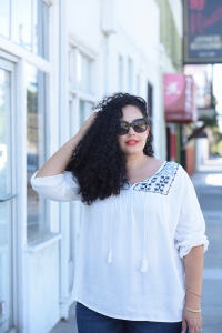 Tanesha Awasthi, also known as Girl With Curves, wearing dark wash plus size skinny jeans, a swing blouse, Celine sunglasses.
