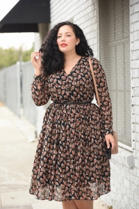 Tanesha Awasthi, also known as Girl with Curves, wearing a long sleeve plus size floral midi dress and a Chanel bag.