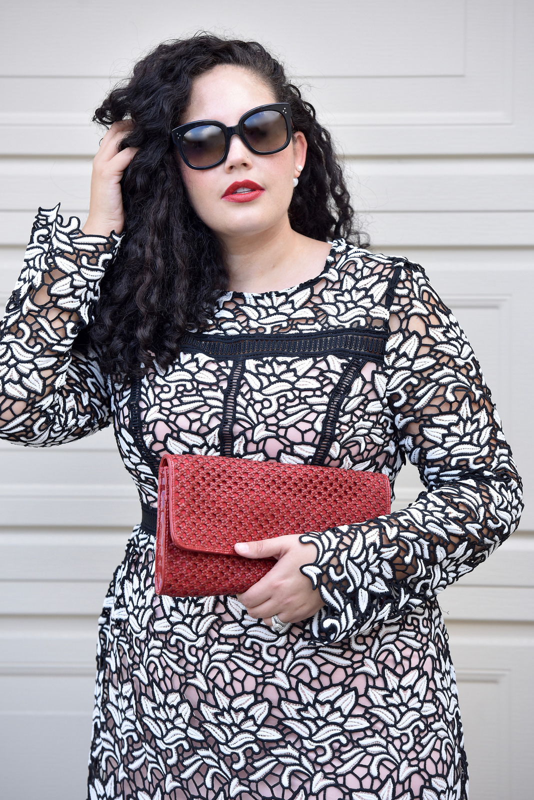 Girl With Curves blogger Tanesha Awasthi wears a lace midi dress and red clutch.