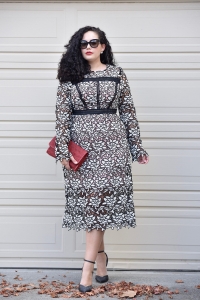 Girl With Curves blogger Tanesha Awasthi wears a lace midi dress, red clutch and ankle strap heels.