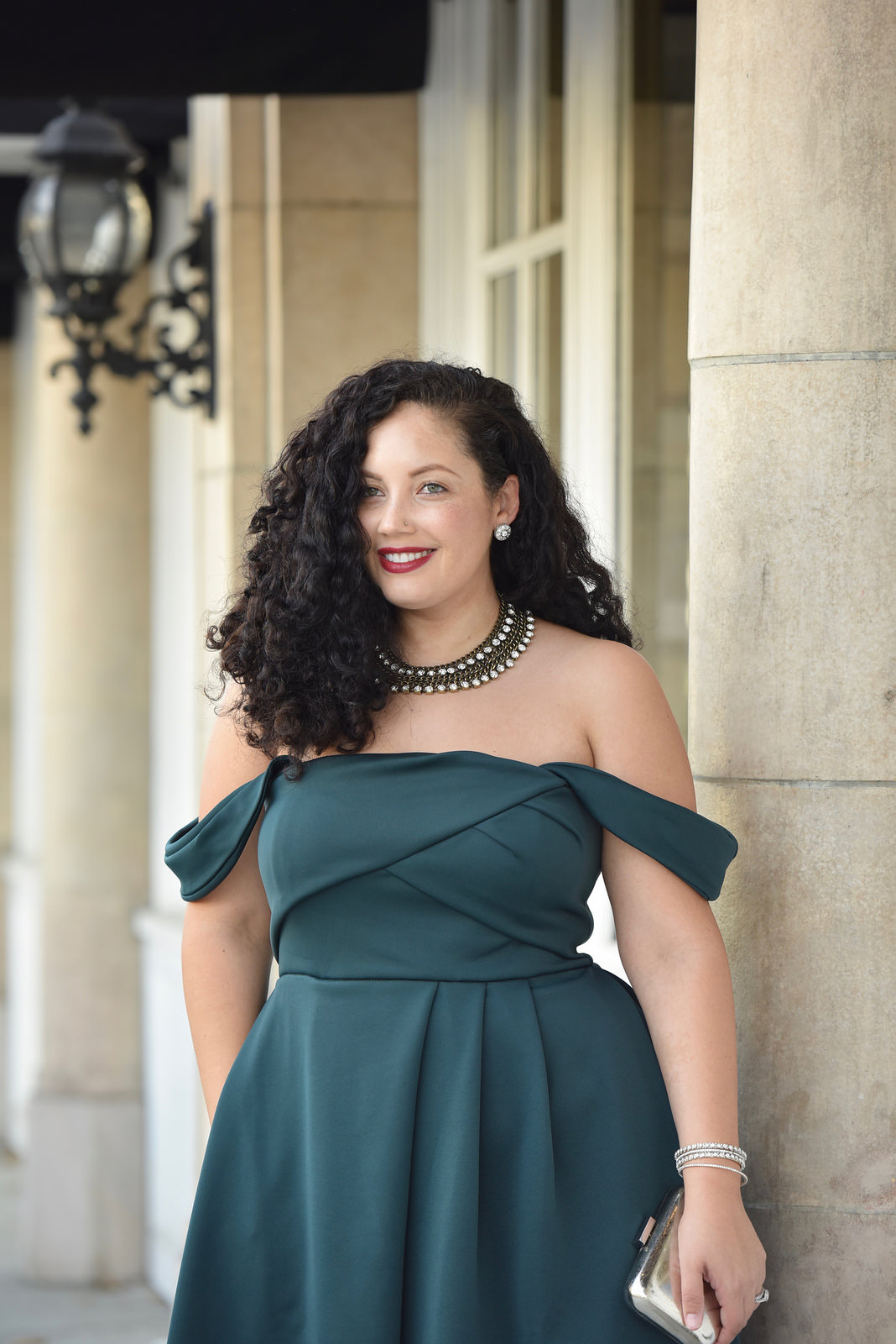 Girl With Curves blogger Tanesha Awasthi wears an emerald off-shoulder dress and statement necklace in downtown San Jose, CA.