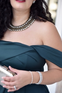 Girl With Curves blogger Tanesha Awasthi wears an emerald off-shoulder dress, silver box clutch and rhinestone bangles.