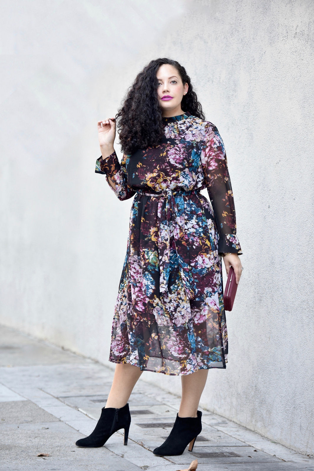Girl With Curves blogger Tanesha Awasthi wears a long sleeve floral print dress midi dress and booties.