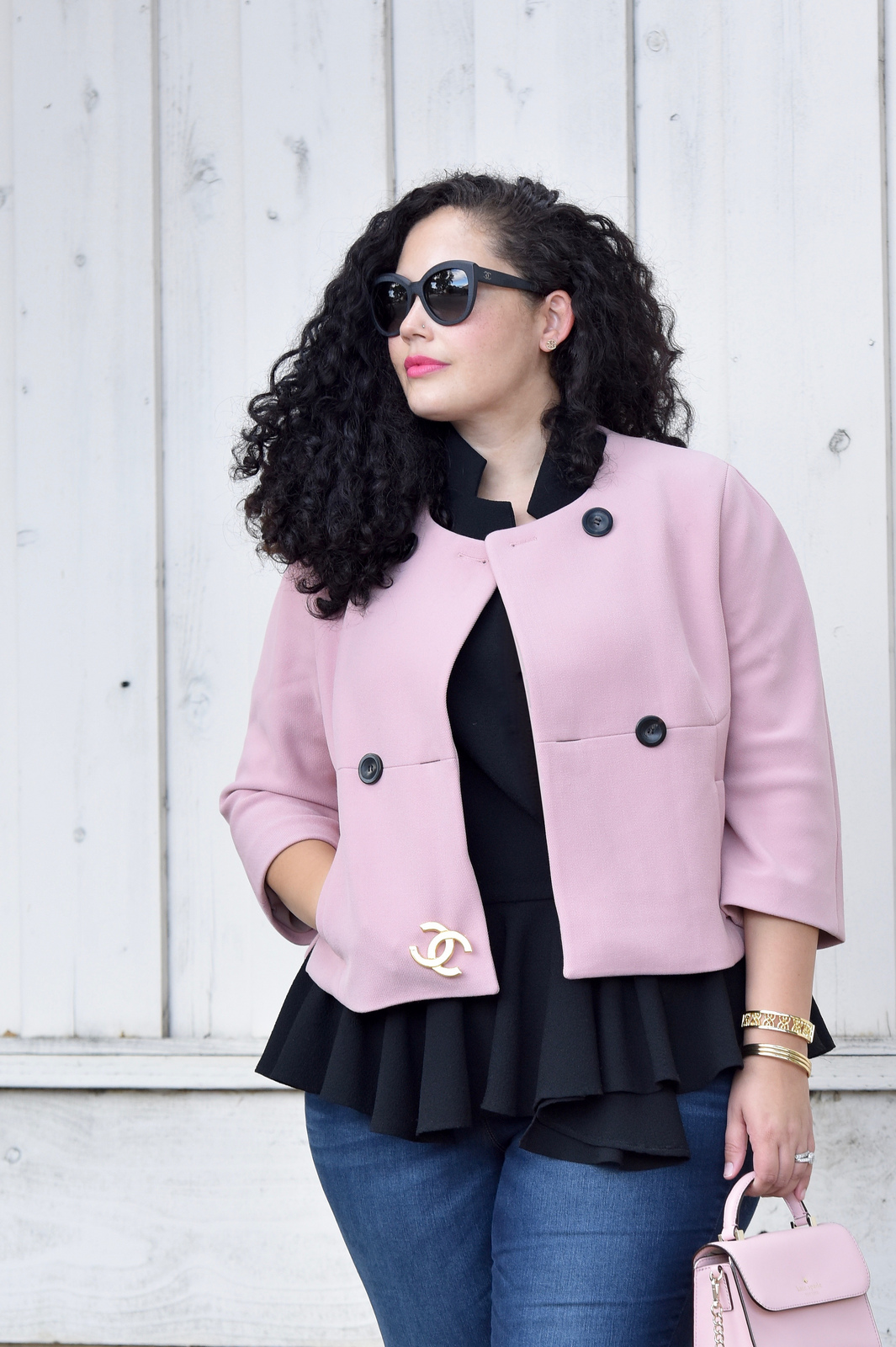 Girl With Curves blogger Tanesha Awasthi wears a pink cropped jacket, peplum top, skinny jeans.