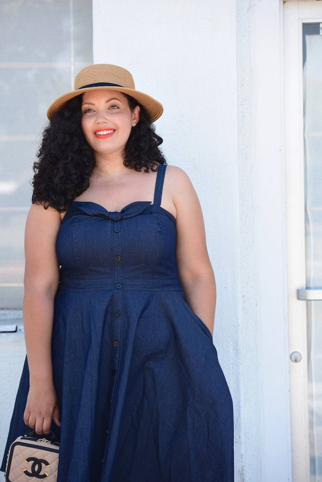 Girl With Curves blogger Tanesha Awasthi wears a denim sundress and boater hat.