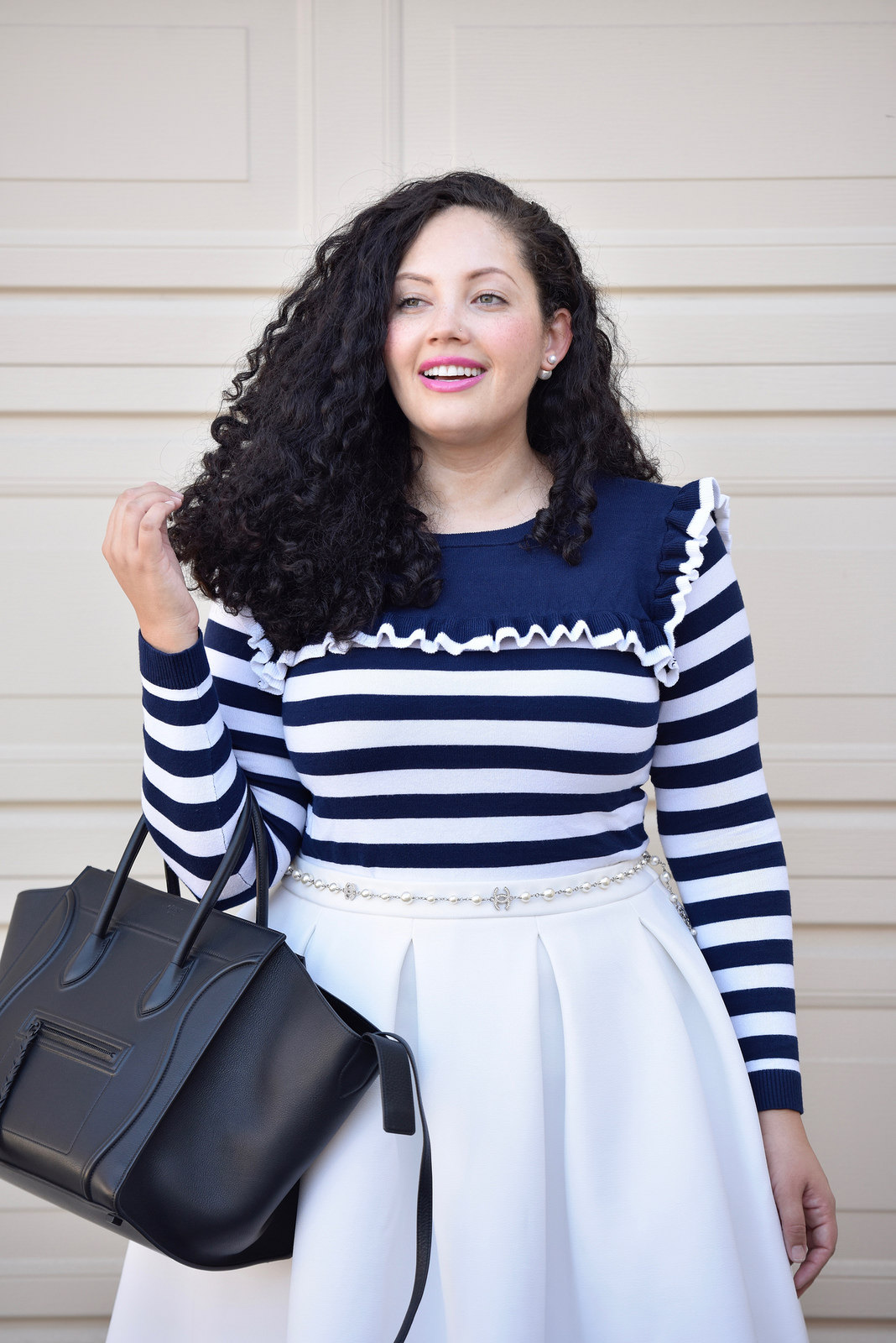 Girl With Curves blogger Tanesha Awasthi wears a stripe ruffle sweater, midi skirt, strappy flats and Celine Phantom bag.