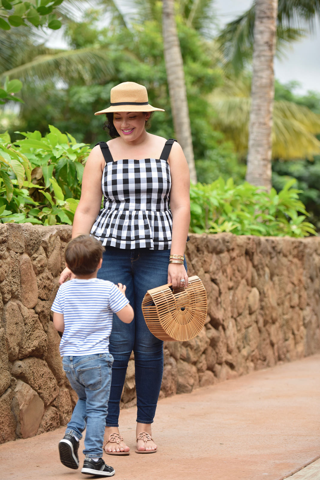 Girl With Curves blogger Tanesha Awasthi wears a gingham peplum and boater hat in Hawaii with her son Narayan.